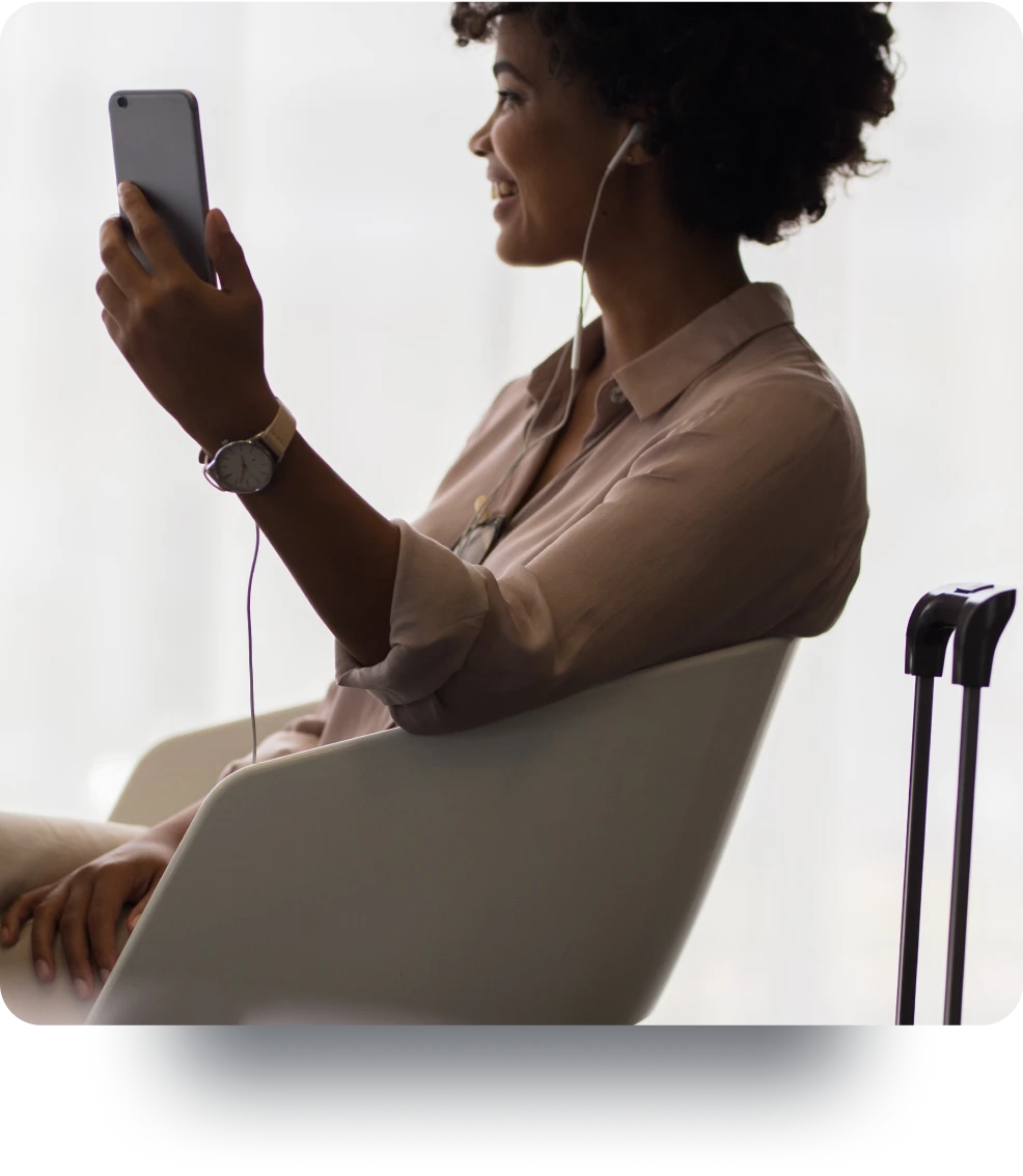 A woman making a video call from a mobile phone while sitting in an airport lounge.